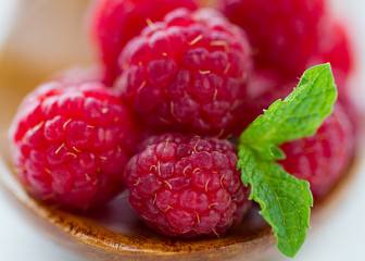 Natural raspberry green leaves on white and wooden background.