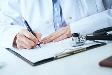 Female medicine doctor hand holding silver pen writing something on clipboard closeup.. Ward round, patient visit check, medical calculation and statistics concept.
