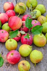 Fresh red apples with green leaves on a wooden old table.
