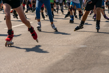 Many legs in roller-blades. People participate in outdoors racing marathon