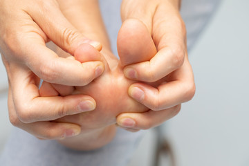 A closeup view of person separating the big toe from the middles toes, barefooted person massages...