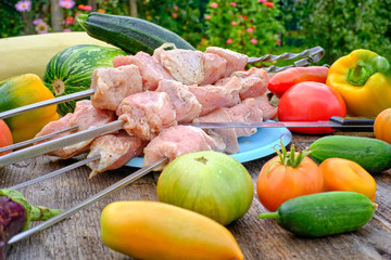 Raw meat for barbecue, lying on an old wooden table in the various derevenskih seasonal vegetables