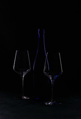 Bottle and glass of red wine on black background