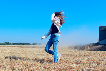 Carefree and attractive young woman in a wheat field. People, nature, farming concept. Young girl walking outdoors.