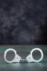Handcuffs on table against dark wall with copy space