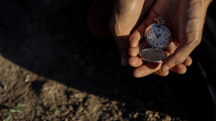 A man is holding antique watches in a hand.