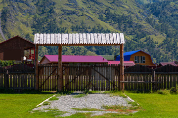 Wooden gate with a fence and a canopy from the rain on a country villa in the mountains with a green lawn in the yard. © Aleksandr Kondratov