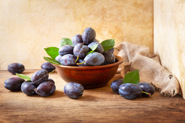 bowl of fresh plums with leaves
