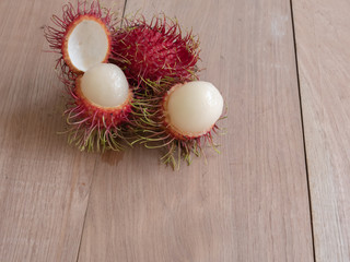 Red rambutan fruit on a plate on wooden background.
