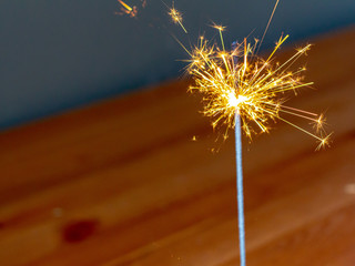 Sparks are flying as the explosive light of a sparkler descends down its stick, consuming the...