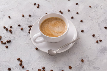 A cup of delicious hot cappuccino and beans on a gray concrete table