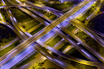 Aerial view of illuminated road interchange or highway intersection with busy urban traffic...