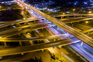 Fototapeta na wymiar Aerial view of illuminated road interchange or highway intersection with busy urban traffic speeding on the road at night. Junction network of transportation taken by drone.