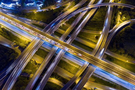 Aerial view of illuminated road interchange or highway intersection with busy urban traffic speeding on the road at night. Junction network of transportation taken by drone. © zephyr_p