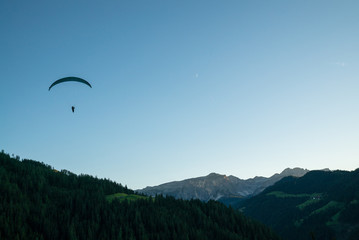 silhouette of paraglider in Dolomite mountain landscape in evening light