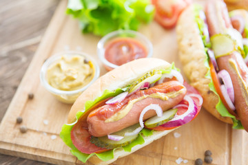 Delicious fast food. Hot dogs with vegetables on wooden table