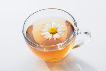 Glass cup with herbal tea with chamomile flowers