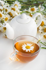 Glass cup with herbal tea with chamomile flowers