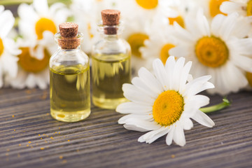 Obraz na płótnie Canvas Glass bottle with essential aroma chamomile oil with flowers