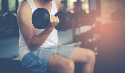 Fitness man exercising are lifting dumbbells. Fitness muscular body at fitness gym. Working out with dumbbell weights at the gym. fitness, sport, training, gym and lifestyle concept.