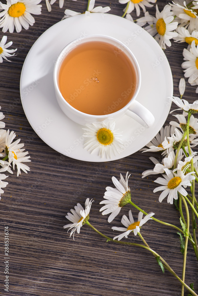 Wall mural Cup of chamomile herbal tea with flowers