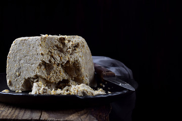 Big piece of sunflower and sesame halva on wooden table against black background. Eastern dessert