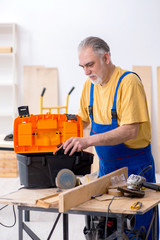 Old male carpenter working in workshop