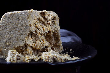 Big piece of sunflower and sesame halva on wooden table against black background. Eastern dessert