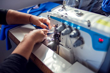 Woman works with sewing machine. Manufacture of wearing concept