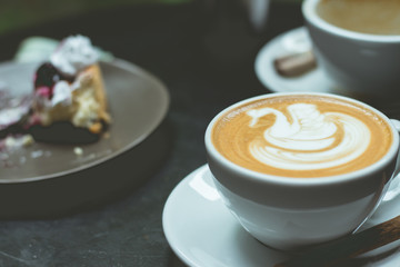 hot art latte heart and blueberry cheesecake on table.