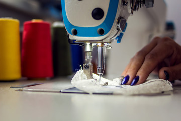 Woman works with sewing machine. Manufacture of wearing concept