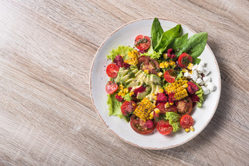 salad with avocado, corn, tomato and spinach leaves