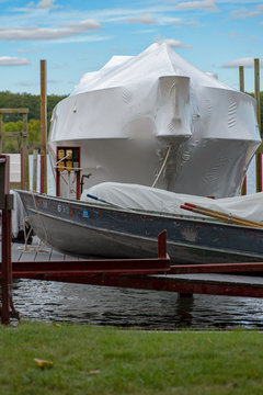Rowboat in front of shrink wrapped boat