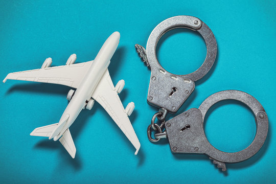 Airplane And Handcuffs On The Table, Top View. Concept On The Topic Of Hooliganism On Board An Aircraft