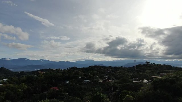 AERIAL Mountainous Backdrop Over A Tropical Forest And Township