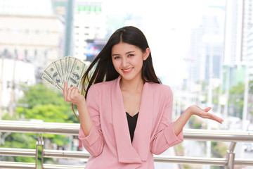 Cheerful Asian woman holding money banknotes and happy income money from her job. pocket money to...