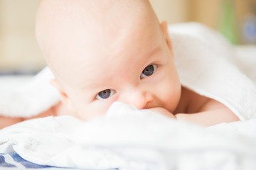 Adorable baby boy in white sunny bedroom. Newborn child relaxing in bed. Nursery for young children. Textile and bedding for kids. Family morning at home
