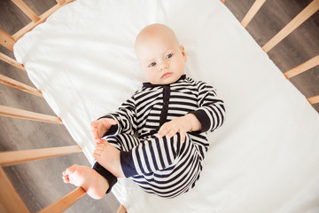 Newborn baby lying in bed in striped clothes