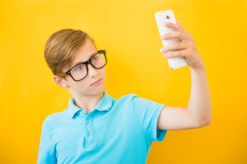 Happy boy making selfie on yellow background