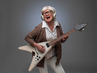 Senior woman playing electric guitar