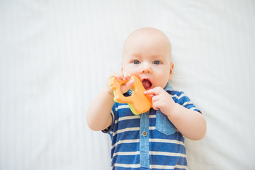 Cute newborn baby takes a wooden toy in his mouth. Teething and health concept