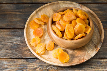 Dried apricots in a wooden bowl on a wooden table