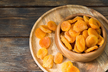 Dried apricots in a wooden bowl on a wooden table