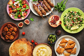 Assorted variety of Arabic and Middle Eastern food on a dark rustic background. Hummus,tabbouleh salad, salad Fattoush,pita,meat kebab,falafel,baklava. Set of Arabian dishes.Top view.