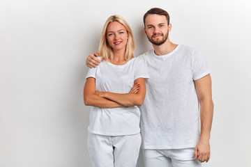 Obraz premium bearded smiling handsome man hugs a woman by the shoulder on a white background, love, relationship, lifestyle, family concept