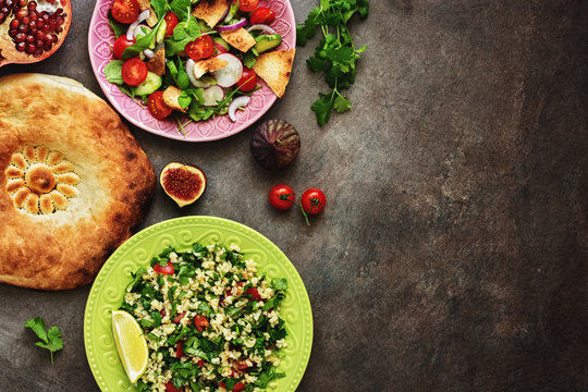 Middle Eastern Salads Tabbouleh And Fattoush, Pitta Bread, Pomegranate, Figs On A Dark Rustic Background. Arabic Dishes, Top View.