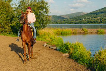girl on a brown horse by the pond