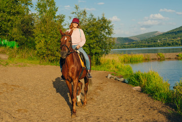 girl on a brown horse by the pond