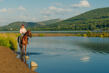 girl on a brown horse by the pond