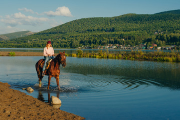 girl on a brown horse by the pond